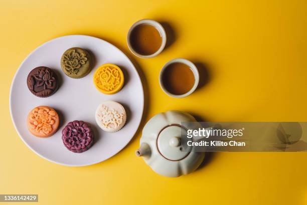 overhead view of a plate full of mooncakes with exquisite flora pattern and  tea set against yellow background - cup of tea from above stock pictures, royalty-free photos & images