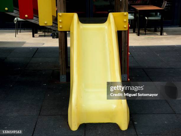 yellow slide in a playground - rutsche stock-fotos und bilder