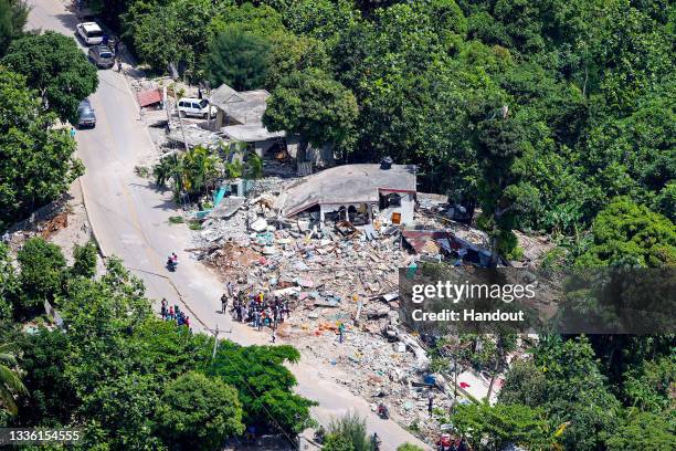 In this handout image provided by the Ministry of Defence, peopple gather near collapsed houses on August 20, 2021 in Les Cayes, Haiti. Rescue...