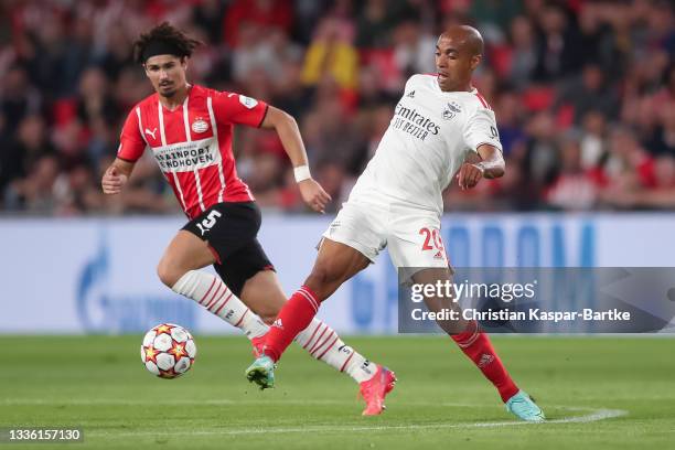 Joao Mario of SL Benfica is tackled by Andre Ramalho of PSV Eindhoven during the UEFA Champions League Play-Offs Leg Two match between PSV Eindhoven...