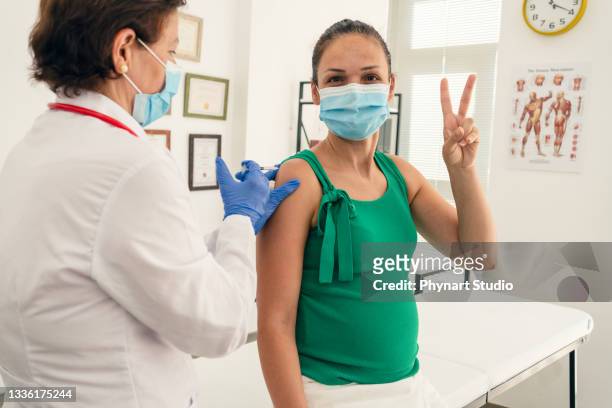 mujer embarazada recibiendo su segunda dosis de una vacuna contra el covid-19 - second test fotografías e imágenes de stock