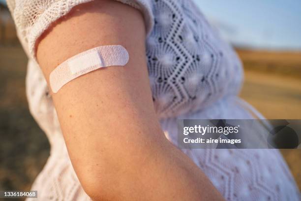 close-up of band aid, on the arm young pregnant woman after giving her the vaccine - beauty shot of young woman stock-fotos und bilder