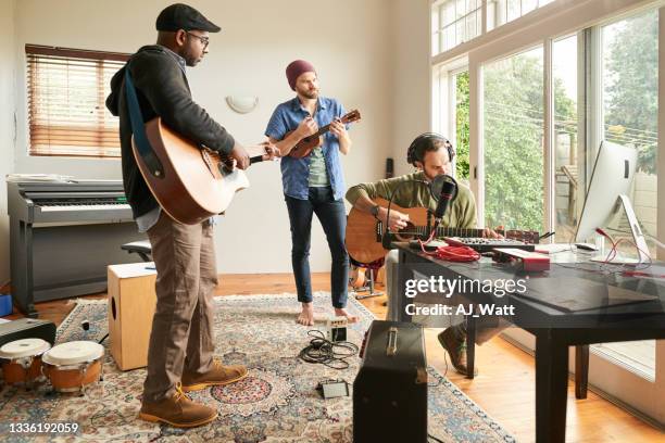 band playing acoustic instruments during a band rehearsal in a home studio - home hobbies stock pictures, royalty-free photos & images