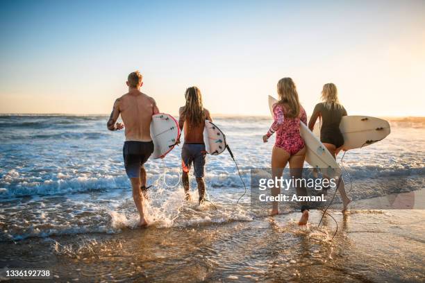 surfers with boards running into water at burleigh heads - burleigh beach stock pictures, royalty-free photos & images