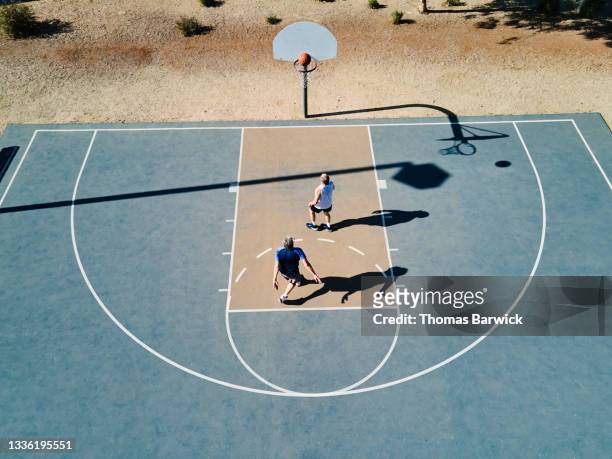 Wide shot elevated view of senior men playing basketball on summer morning