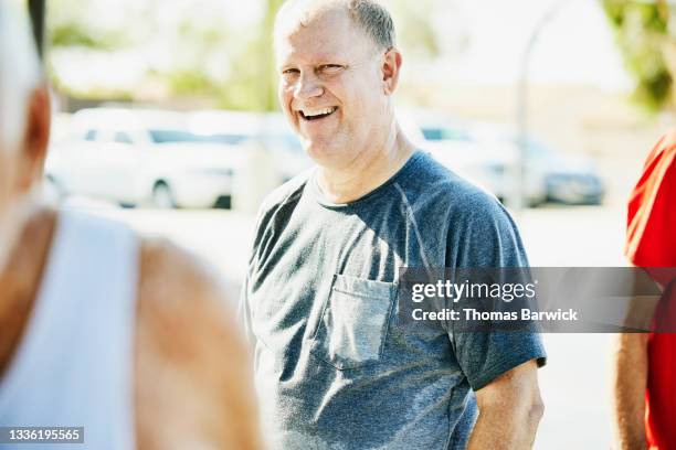 medium shot of laughing mature man hanging out with friends after morning basketball game - 55 years old white man active stock pictures, royalty-free photos & images