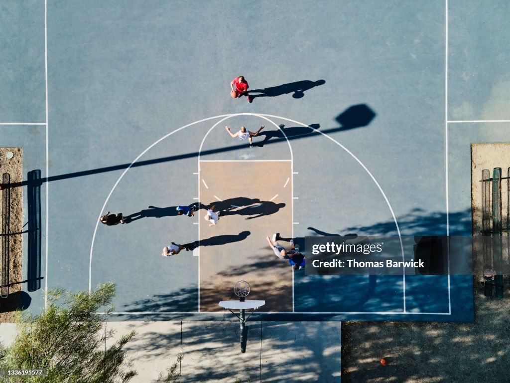 Wide shot overhead view of senior men playing basketball game on summer morning
