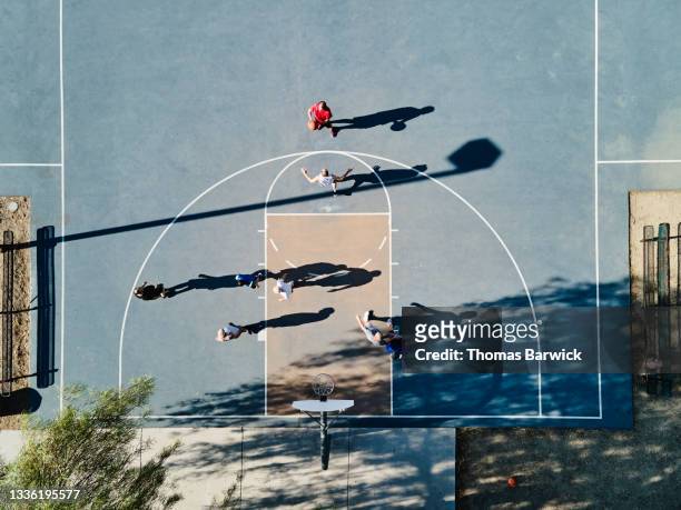 Wide shot overhead view of senior men playing basketball game on summer morning