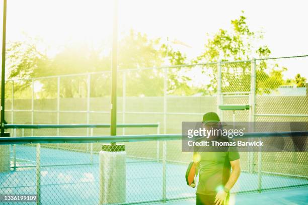 medium wide shot of laughing senior man playing pickleball on summer evening - racket sport fotografías e imágenes de stock
