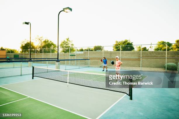 Extreme wide shot of senior women playing doubles pickleball match on summer evening
