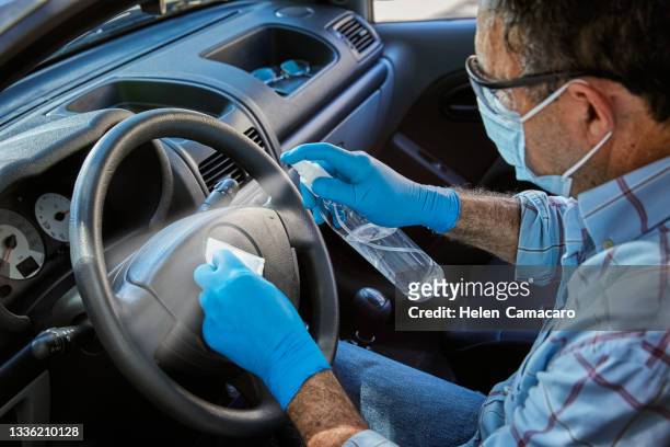 close up of hands with gloves applying spray alcohol and cleaning interior car - killing germs stock pictures, royalty-free photos & images