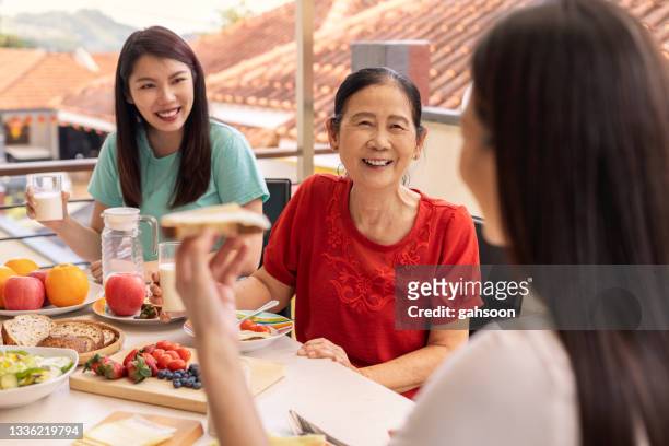 家庭で一緒に健康的な朝食を食べる幸せな家族 - chinese eating backyard ストックフォトと画像