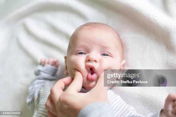 hand of mother squeezing cheeks of baby son - cheek stock pictures, royalty-free photos & images