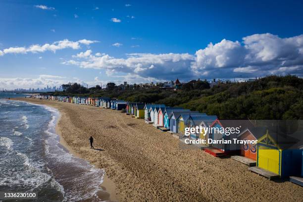 In an aerial view, a man walks along Brighton Beach on August 25, 2021 in Melbourne, Australia. Victoria has expanded its COVID-19 vaccination...