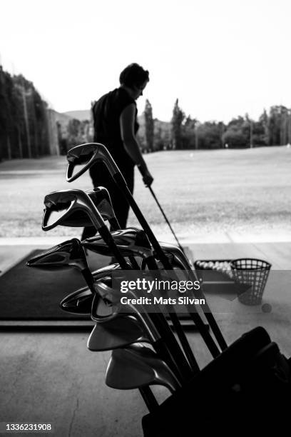 golfer practice in driving range and a golf bag with golf clubs - bolsa de golf fotografías e imágenes de stock