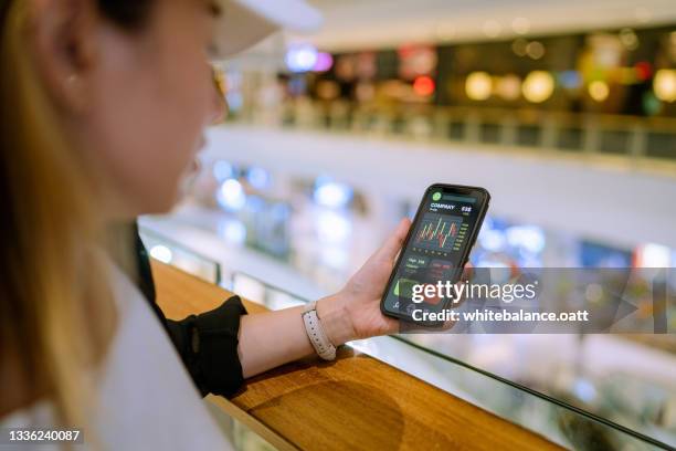 woman wearing a hat checking stocks and eating food - bitcoin phone stock pictures, royalty-free photos & images