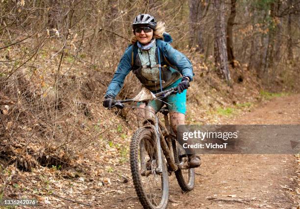 female biker covered by mud riding fast down a trail - muddy footpath stock pictures, royalty-free photos & images