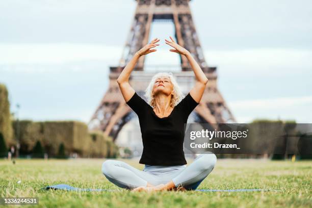 mature woman near eiffel tower doing yoga - paris sport stock pictures, royalty-free photos & images