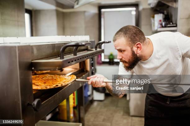 pizza chef working in the kitchen - pizzeria stockfoto's en -beelden