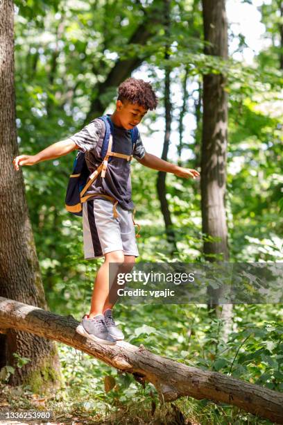 cute african boy balancing on log in the wood - only boys stock pictures, royalty-free photos & images