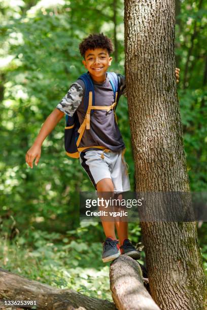 porträt des süßen afrikanischen jungen, der auf baumstamm balanciert - african american hiking stock-fotos und bilder