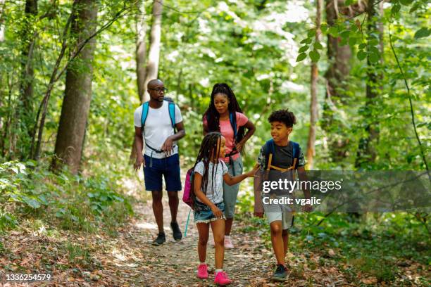 junge afrikanische familie, die die schönheit des waldes genießt - african american hiking stock-fotos und bilder