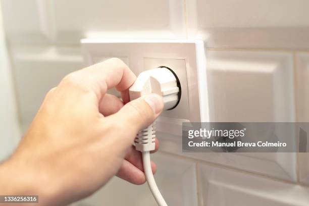 man plugging in an electrical appliance - presa di corrente foto e immagini stock