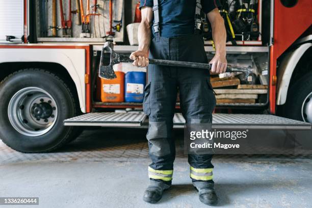 cropped view of an unrecognizable firefighter holding an axe as part of his work tool - fireman axe stock pictures, royalty-free photos & images