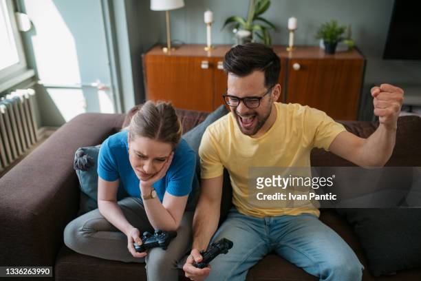 hochwinkelansicht eines glücklichen kaukasischen mannes und einer glücklichen frau, die zu hause videospiele spielen - defeat stock-fotos und bilder