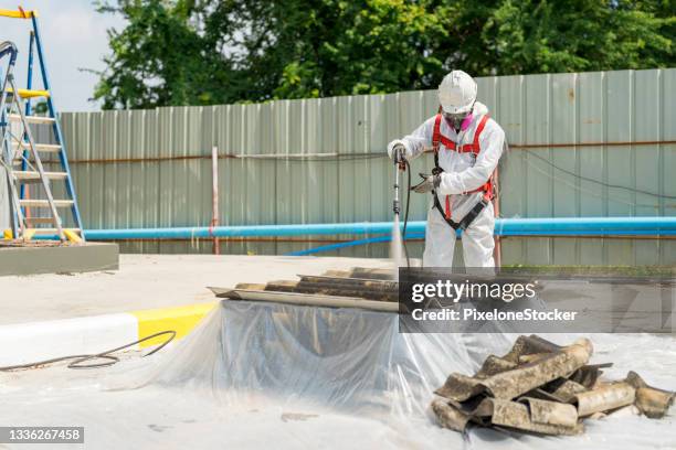 safety is our top priority. worker wearing full body protective clothing while working with the asbestos roof tiles. - asbestos stock pictures, royalty-free photos & images
