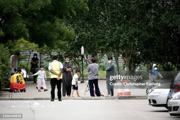 People believed to have recently arrived from Afghanistan stand in the courtyard of a hotel near Manchester Airport on August 25, 2021 in Manchester,...