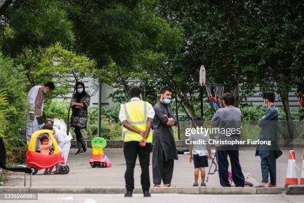 People believed to have recently arrived from Afghanistan stand in the courtyard of a hotel near Manchester Airport on August 25, 2021 in Manchester,...