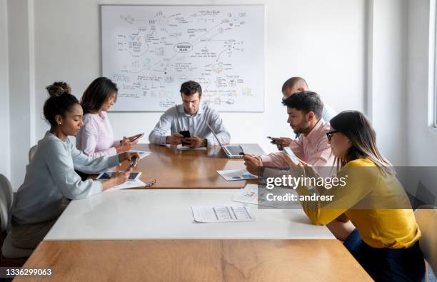 group of business people using smartphones in a meeting at the office - team engagement stock pictures, royalty-free photos & images