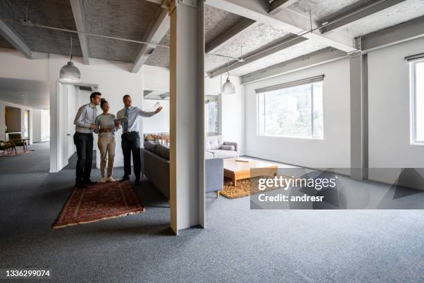 makler, der einem glücklichen paar ein haus im loft-stil zeigt - real estate developer stock-fotos und bilder