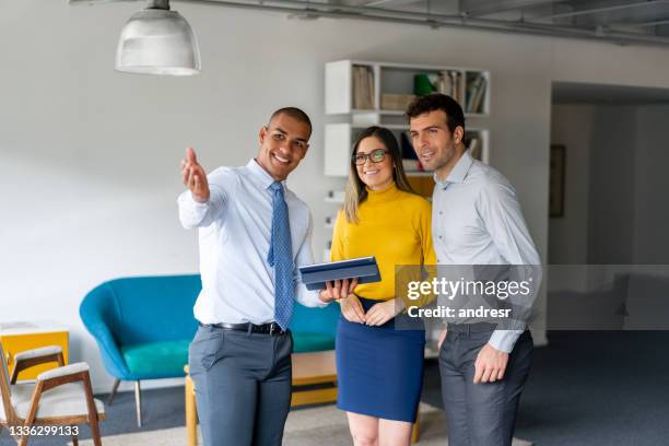 agente de bienes raíces que muestra una propiedad a una pareja feliz - salesman fotografías e imágenes de stock