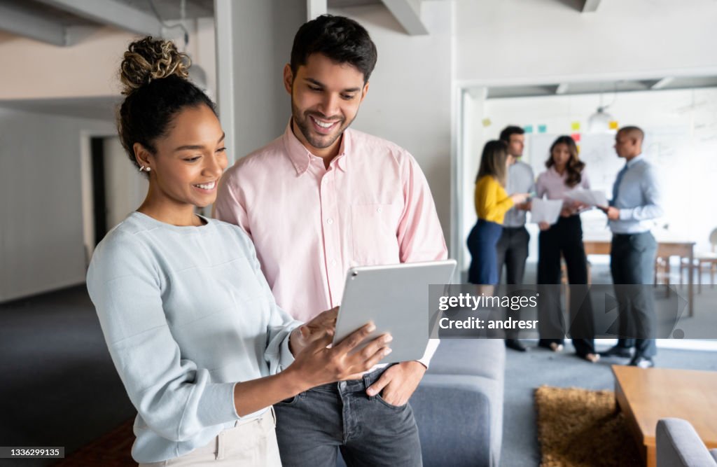 Equipe feliz de trabalhadores no escritório olhando documentos em um tablet
