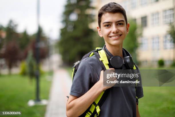 portrait of smiling teenage boy in front of the school - boy headphones imagens e fotografias de stock