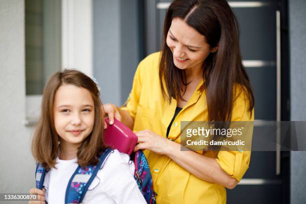 mother preparing her daughter for first day in school - packing kids backpack stockfoto's en -beelden