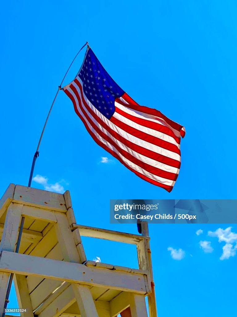 Low angle view of american flag waving against blue sky,Amagansett,New York,United States,USA