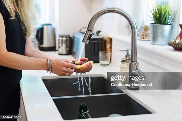 close-up on woman's hands washing vegetables in home kitchen. - kitchen sink stock pictures, royalty-free photos & images