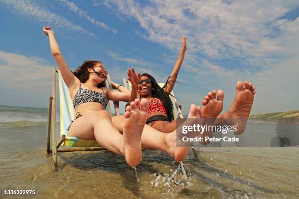 two young women celebrating on deck chairs - legs spread woman stock pictures, royalty-free photos & images