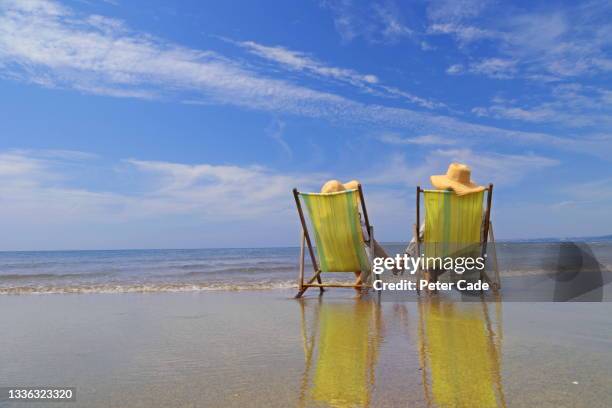 couple in deck chairs on beach - adult summer stock pictures, royalty-free photos & images