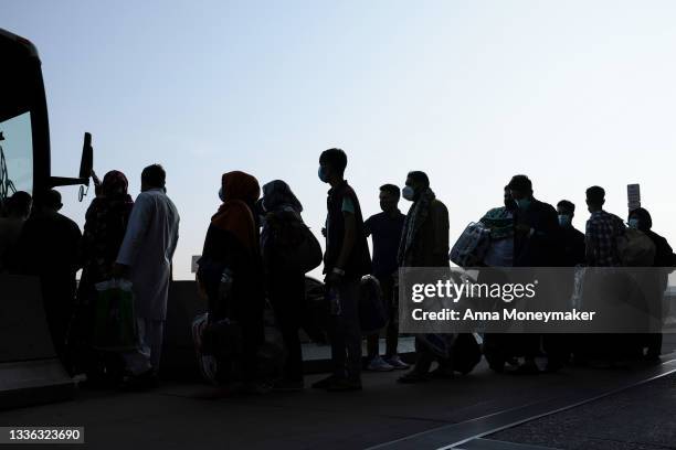 People evacuated from Kabul Afghanistan wait to board a bus that will take them to a refugee processing center at the Dulles International Airport on...