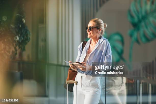 donna d'affari sorridente che ascolta musica sul cellulare in aeroporto - music halls foto e immagini stock