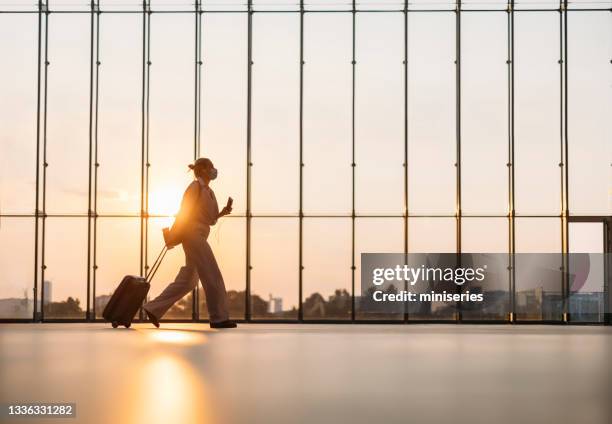 geschäftsfrau beim gehen mit koffer am flughafen - flugzeug sonne stock-fotos und bilder