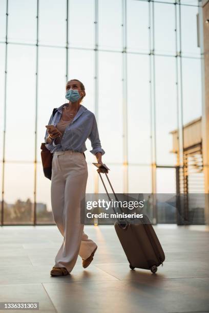 business woman listening to music on mobile phone at the airport - airport mask stock pictures, royalty-free photos & images