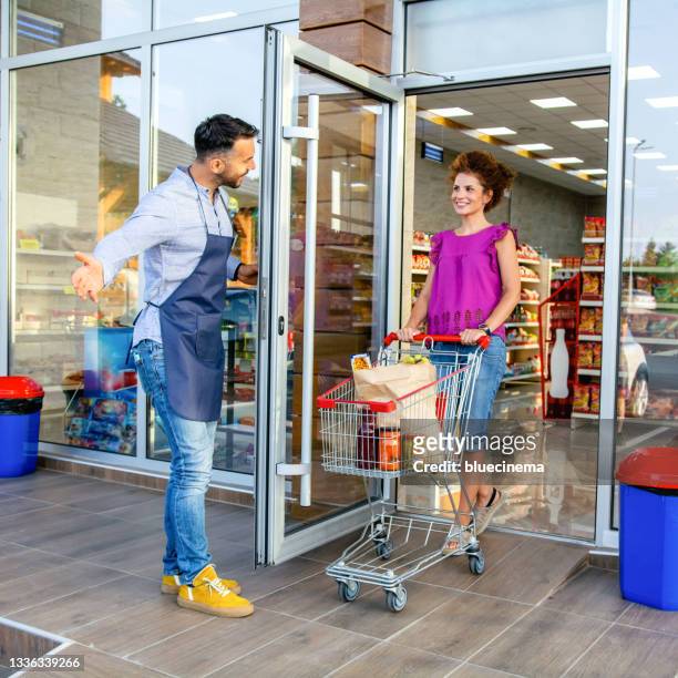 woman leaving a supermarket and pushing shopping cart - leaving store stock pictures, royalty-free photos & images