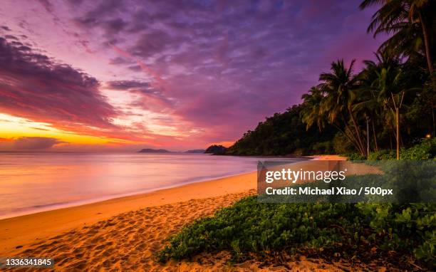 scenic view of beach against sky during sunset,trinity beach,queensland,australia - tropical beach australia stock pictures, royalty-free photos & images