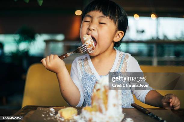 little girl eating a cake - eating cake stockfoto's en -beelden