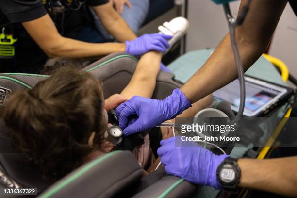 Medics from the Houston Fire Department check the breathing of a Covid-19 positive girl, age 2, before transporting her to a hospital on August 25,...